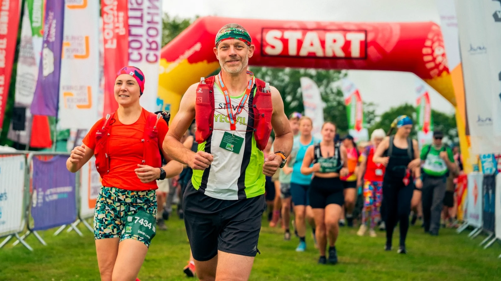 A group of people taking part in Kent Downs 50 Ultra Challenge, running from below a banner with 'Start' on it.