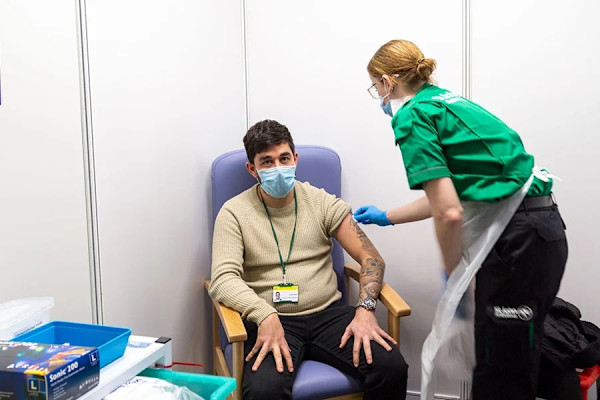 A photograph of Greg receiving a Covid vaccine from a St John volunteer.