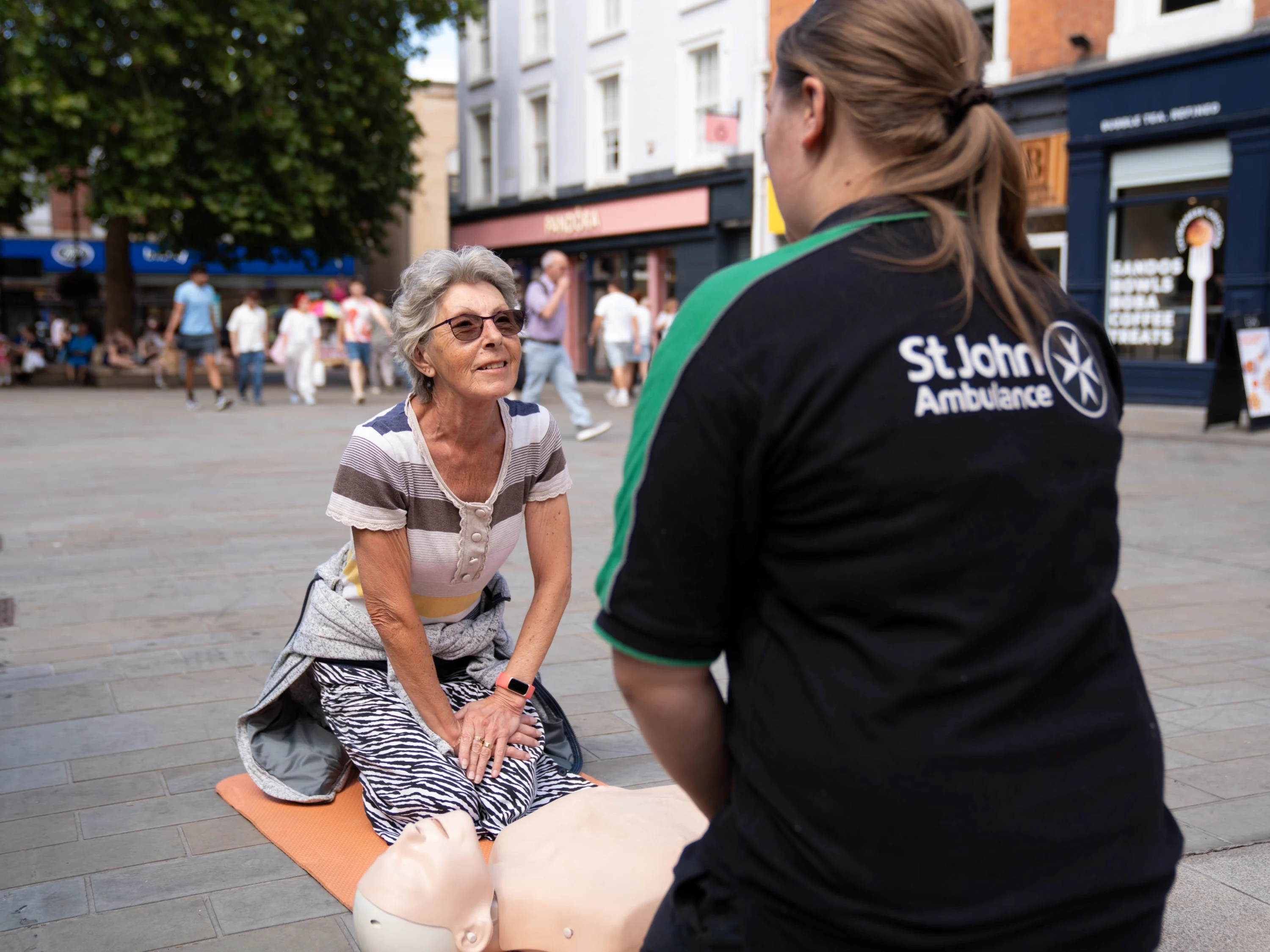 A St John Ambulance trainer giving an older person a free first aid demonstration on the street.