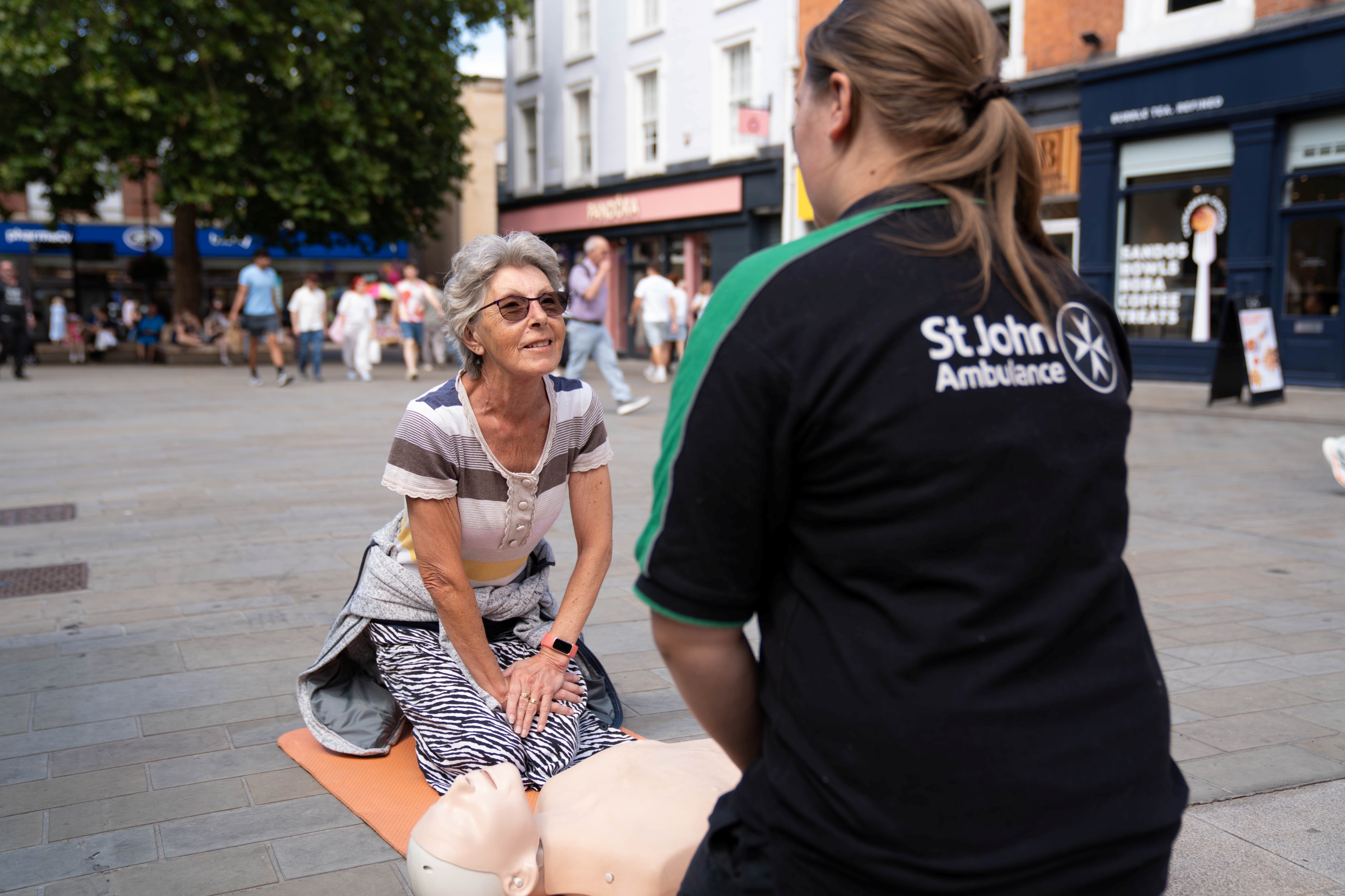 A St John Ambulance trainer giving an elderly lady a free first aid demonstration on the street.