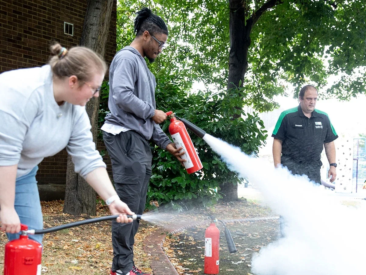 A photograph of people testing fire extinguishers on a fire marshals course