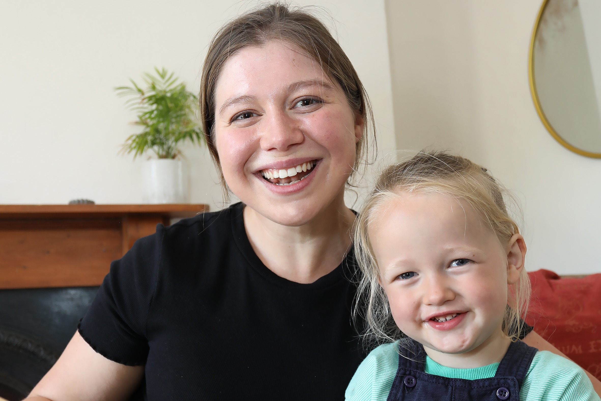 A photograph of Beth and her nephew Roland. They are both smiling at the camera and Beth is holding open a large picture book.