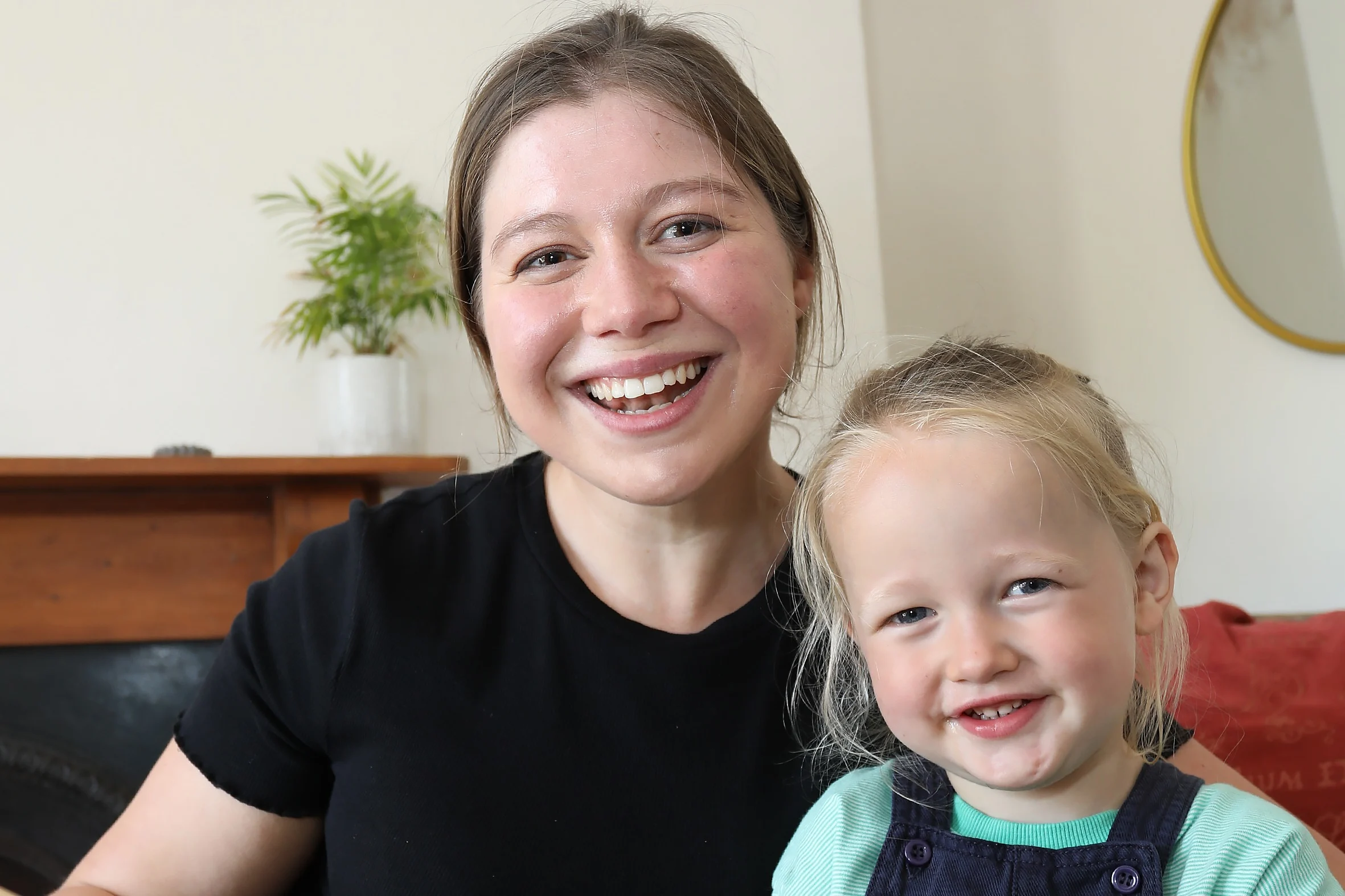 A photograph of Beth and her nephew Roland. They are both smiling at the camera and Beth is holding open a large picture book.