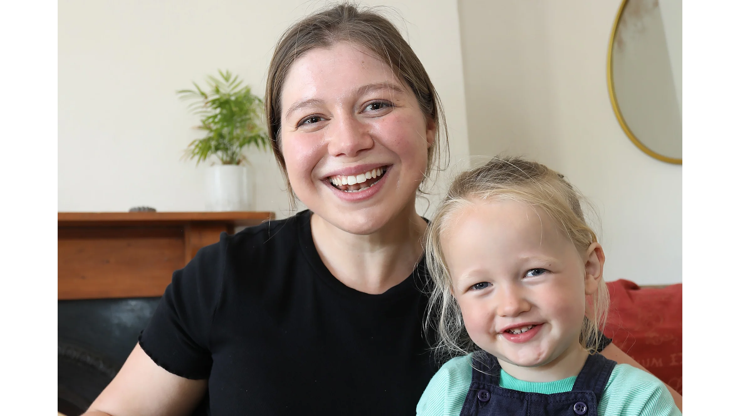 A photograph of Beth and her nephew Roland. They are both smiling at the camera and Beth is holding open a large picture book.