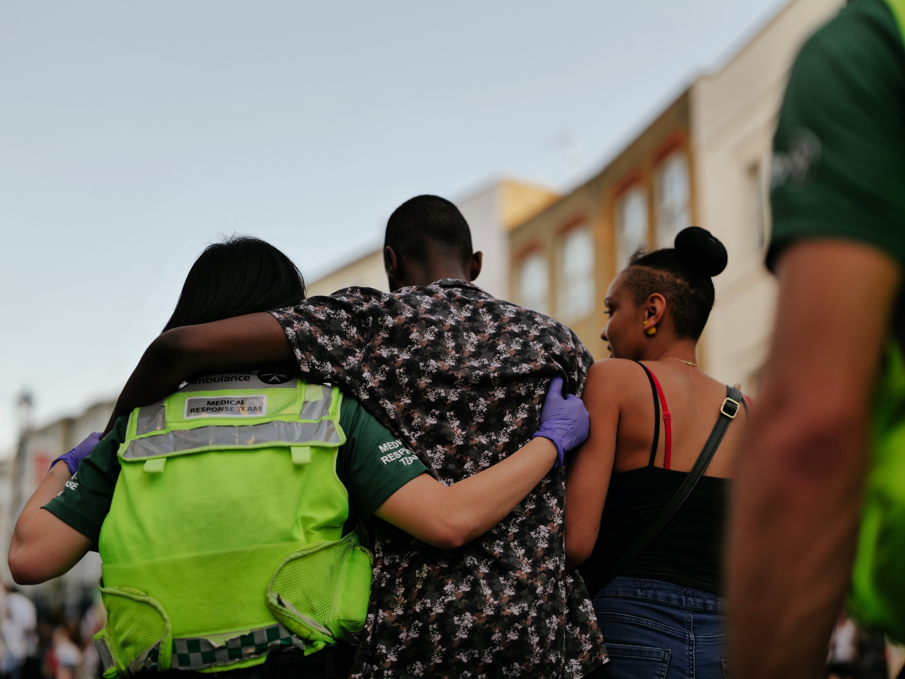 An Event Medical Services volunteer assisting an injured person by walking with them and holding them for support.