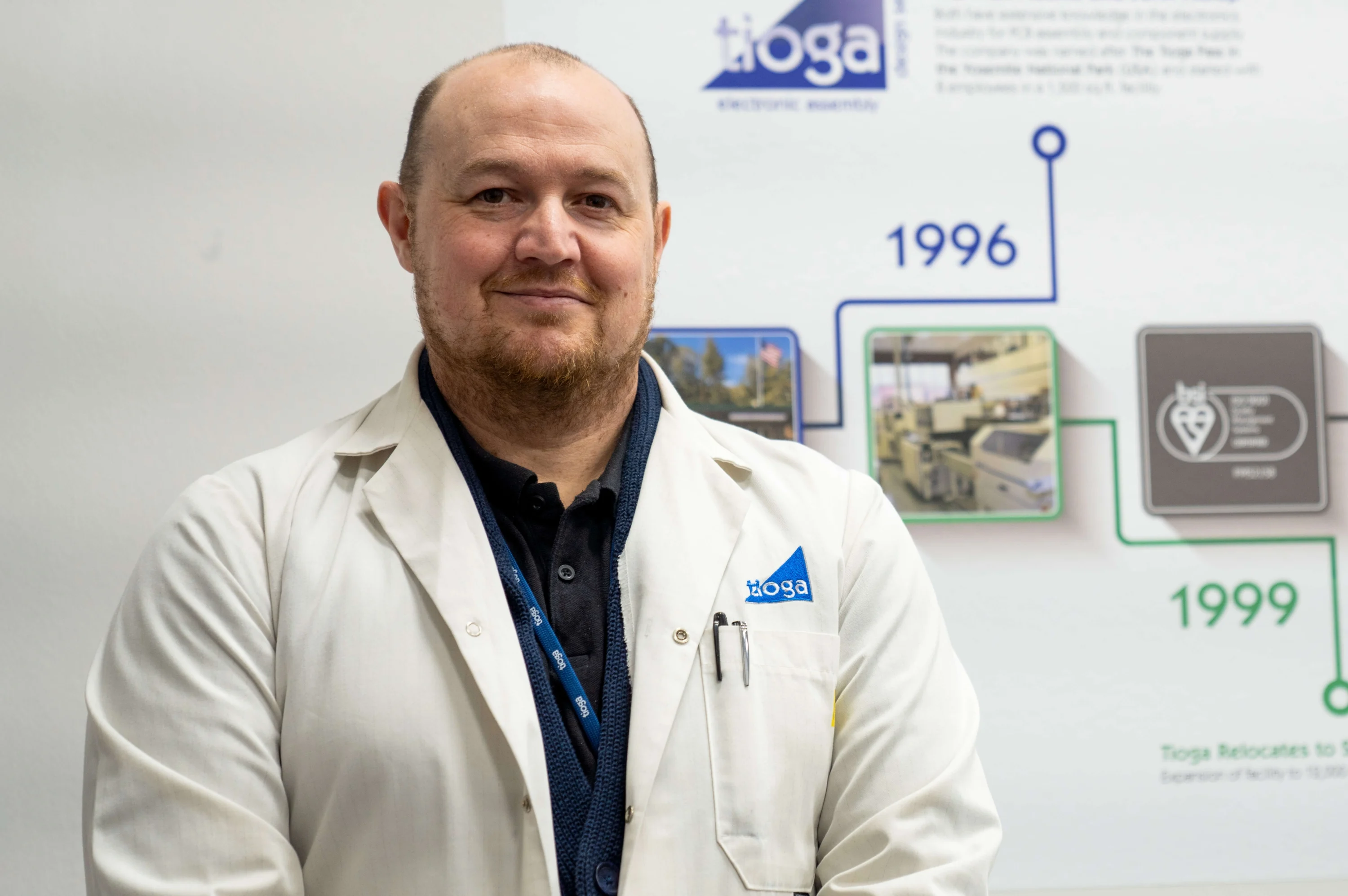 A photograph of Shaun Cardwell wearing a lab coat and smiling at the camera.