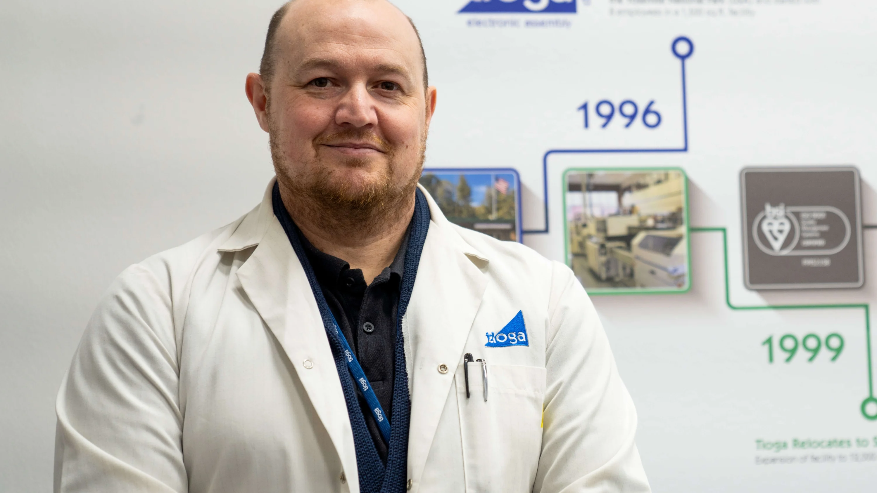 A photograph of Shaun Cardwell wearing a lab coat and smiling at the camera.