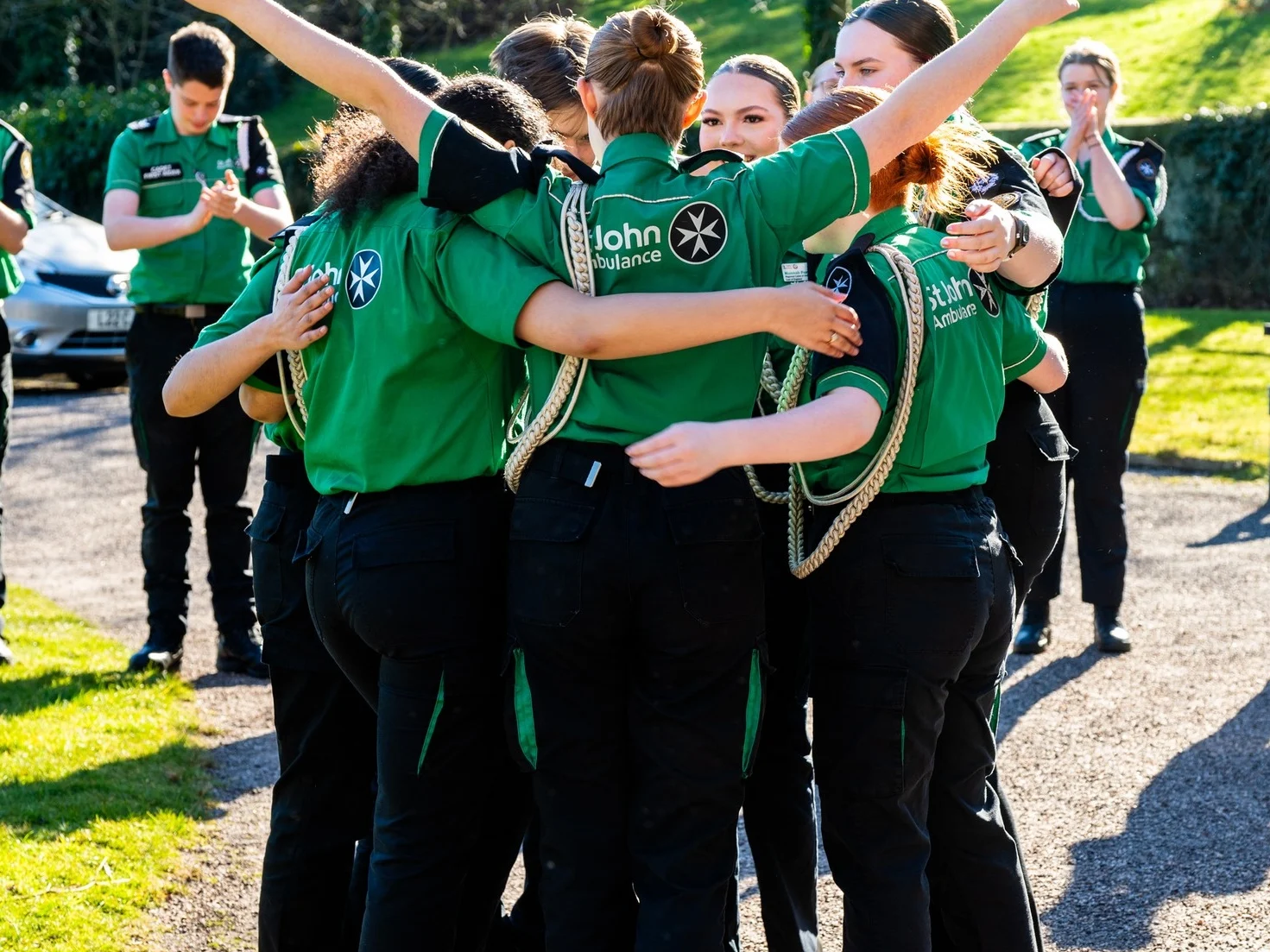 A photograph of a group of Cadets hugging and celebrating in the sunshine.