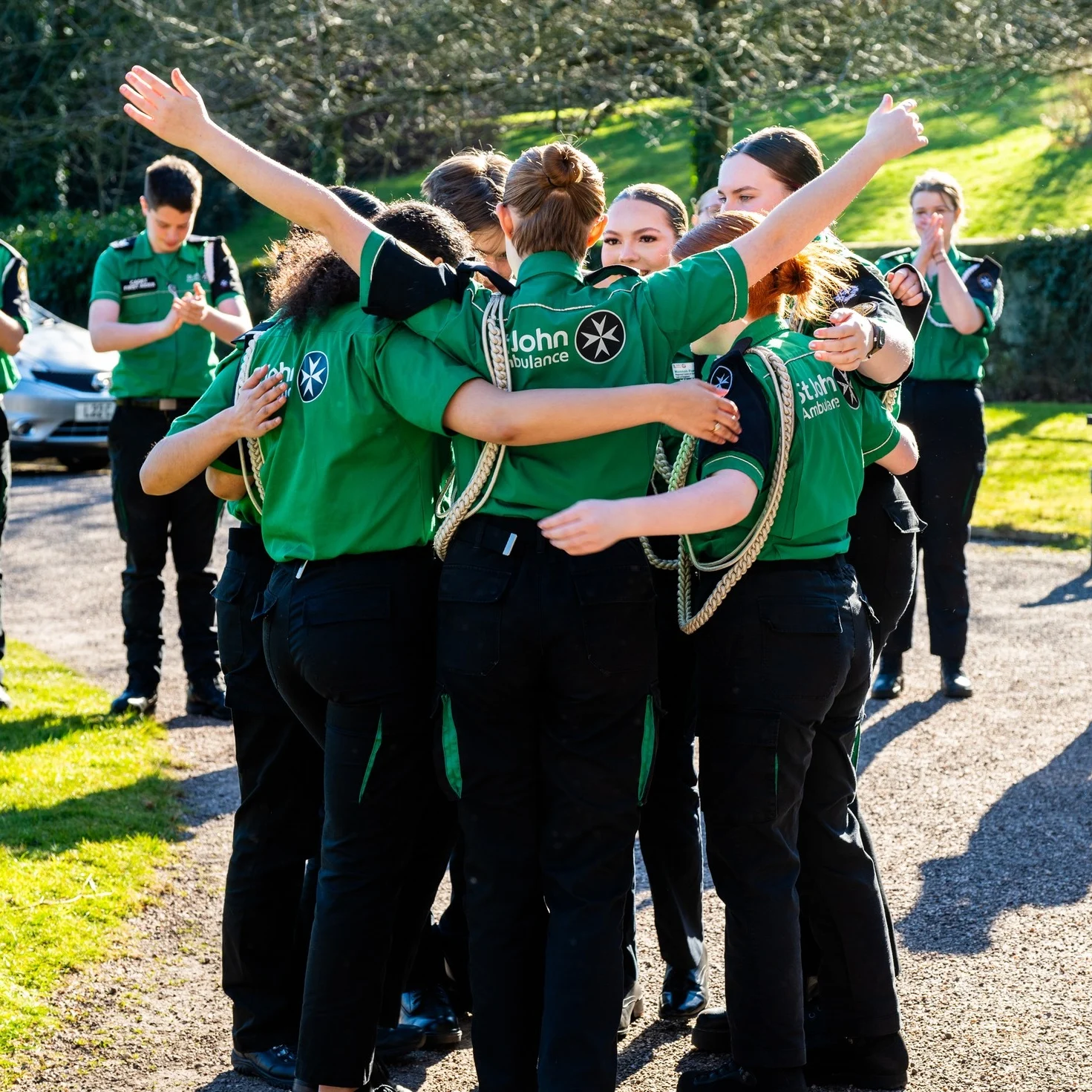 A photograph of a group of Cadets hugging and celebrating in the sunshine.