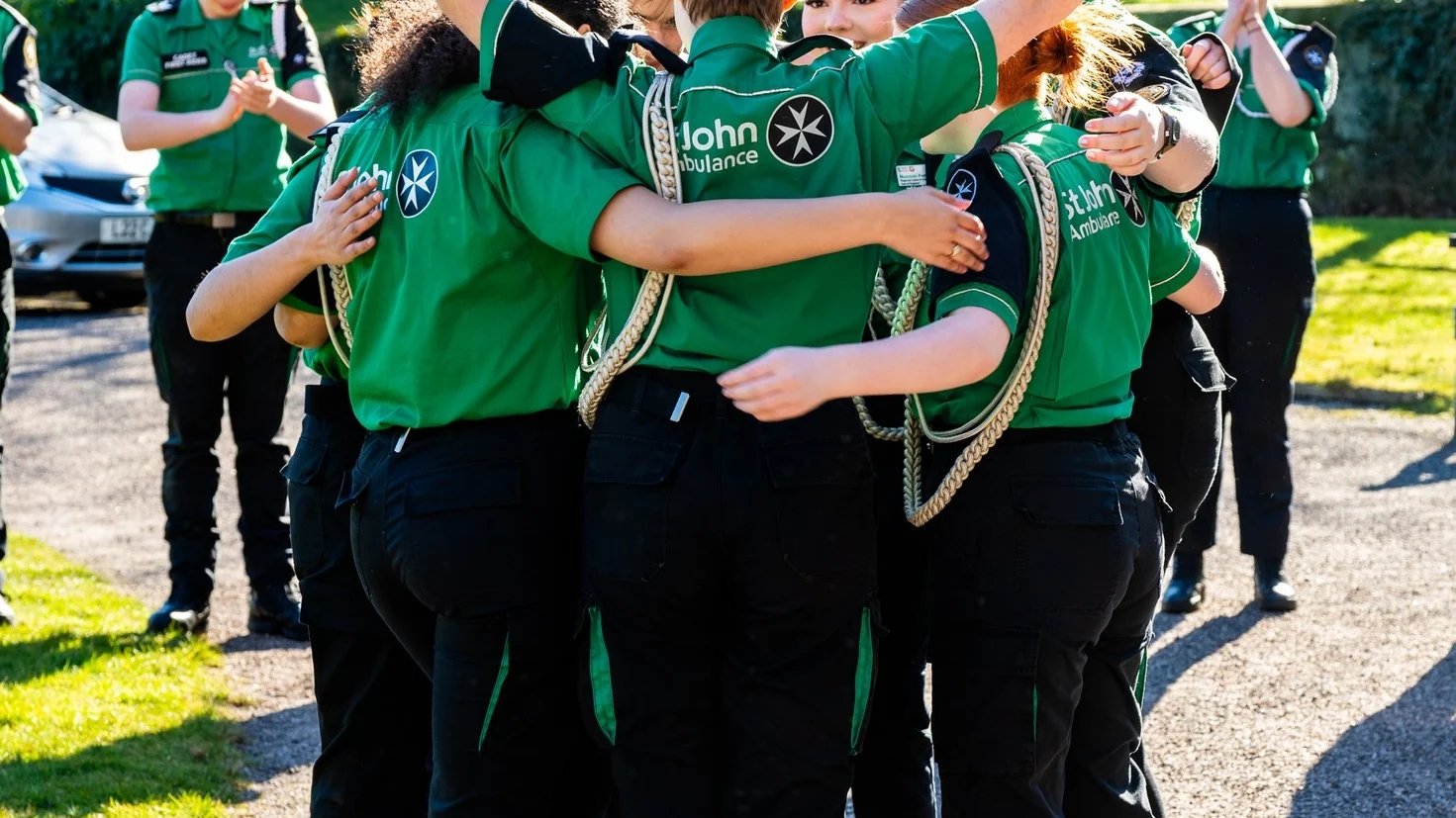 A photograph of a group of Cadets hugging and celebrating in the sunshine.