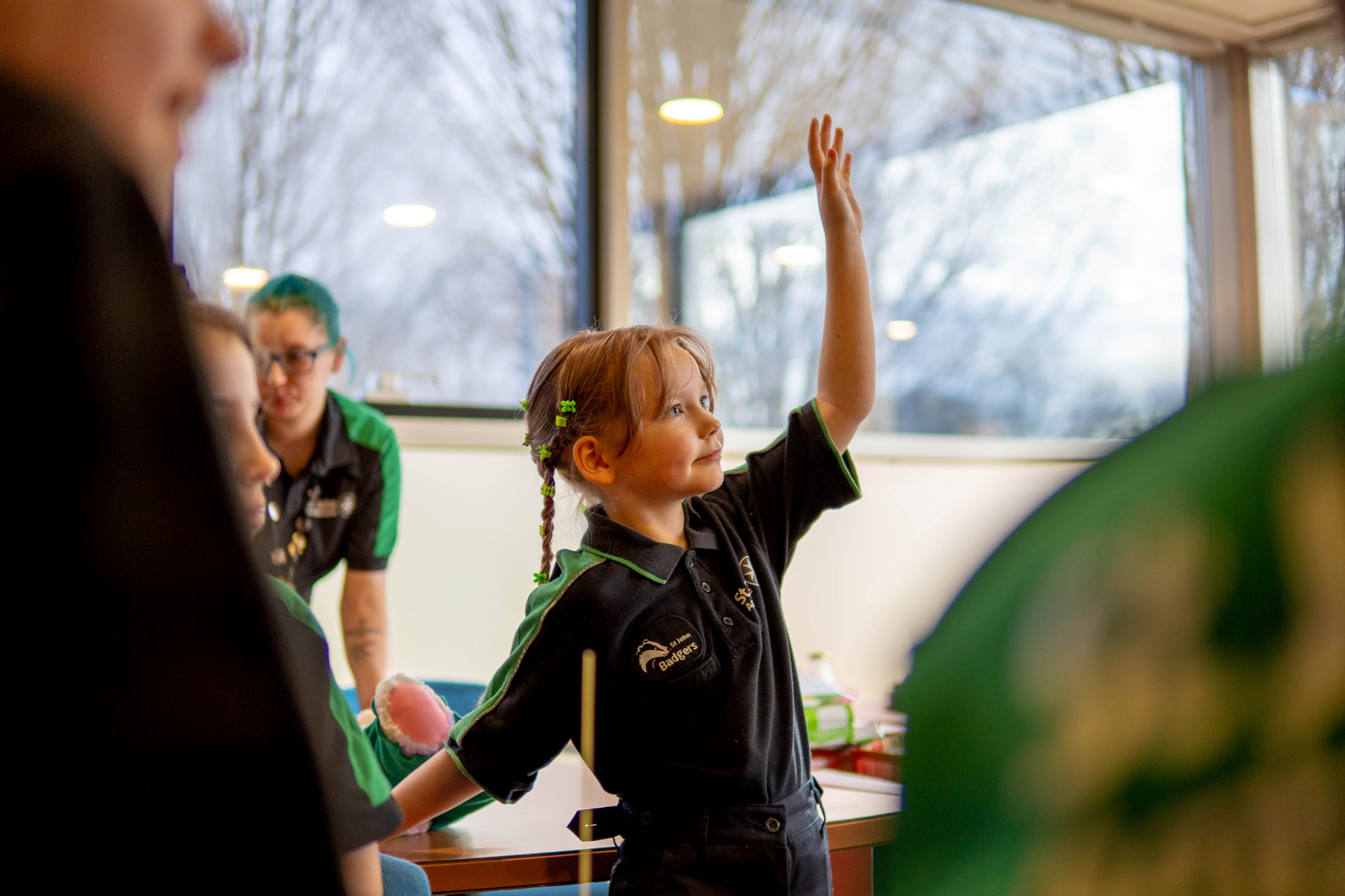 An St John Ambulance Badger raising their hand to answer a question during a session with their Sett.