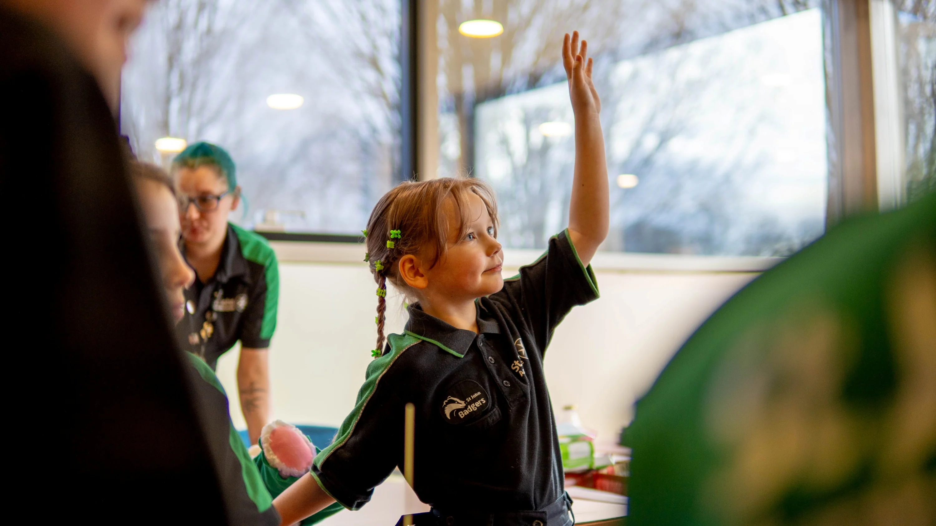 An St John Ambulance Badger raising their hand to answer a question during a session with their Sett.