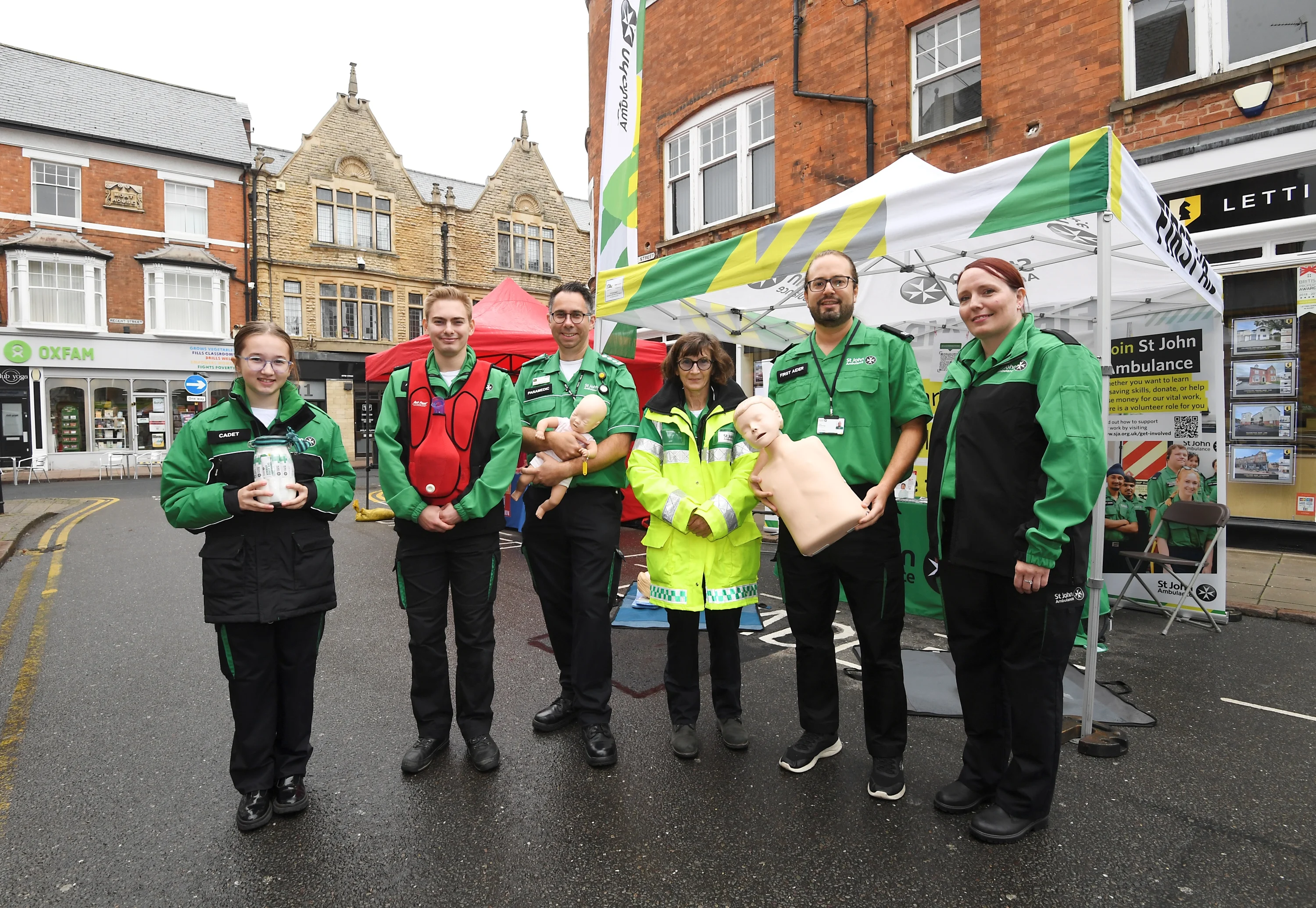 A group of six St john Ambulance first aid trainers in uniform, holding training equipment.