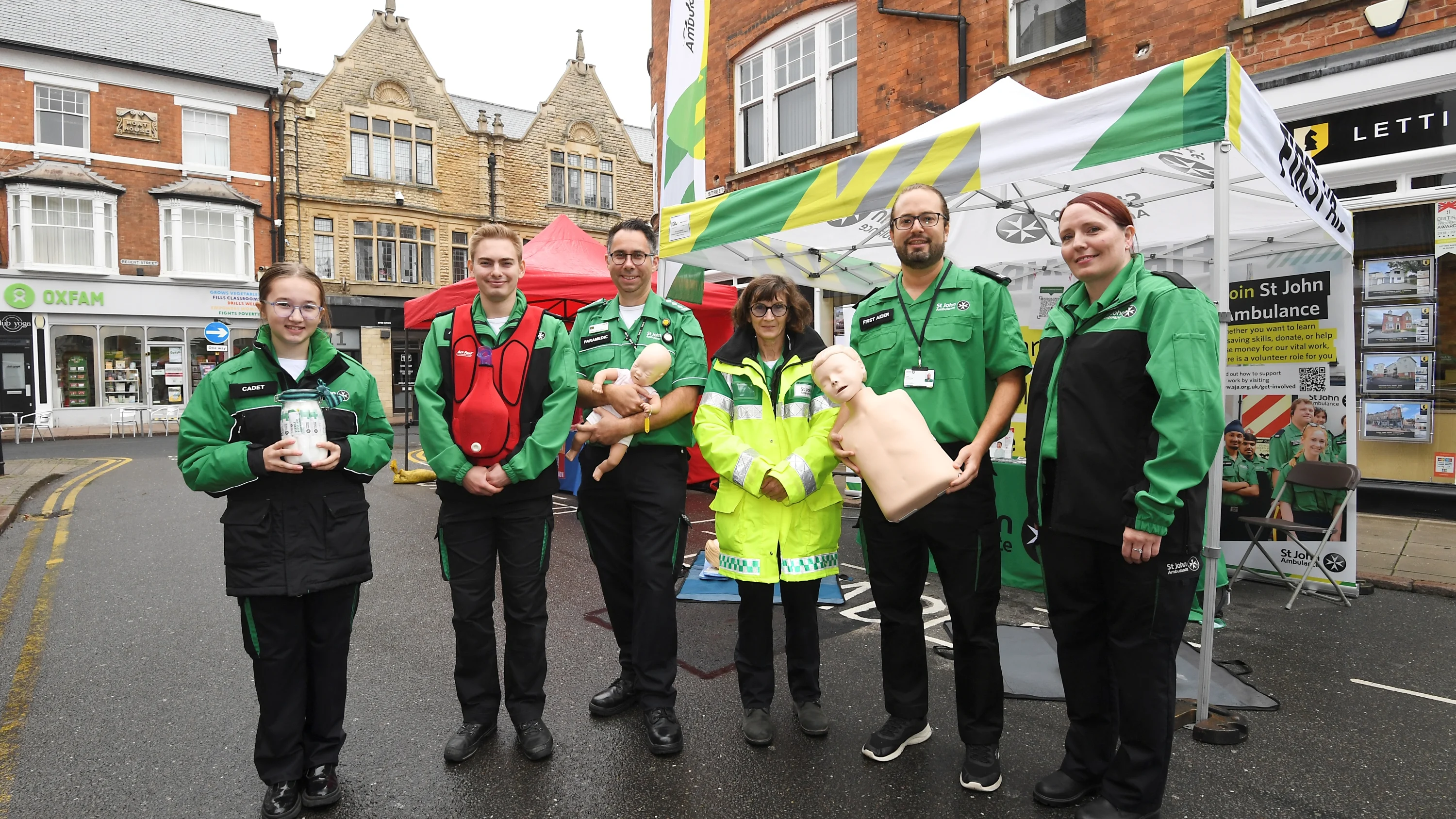 A group of six St john Ambulance first aid trainers in uniform, holding training equipment.