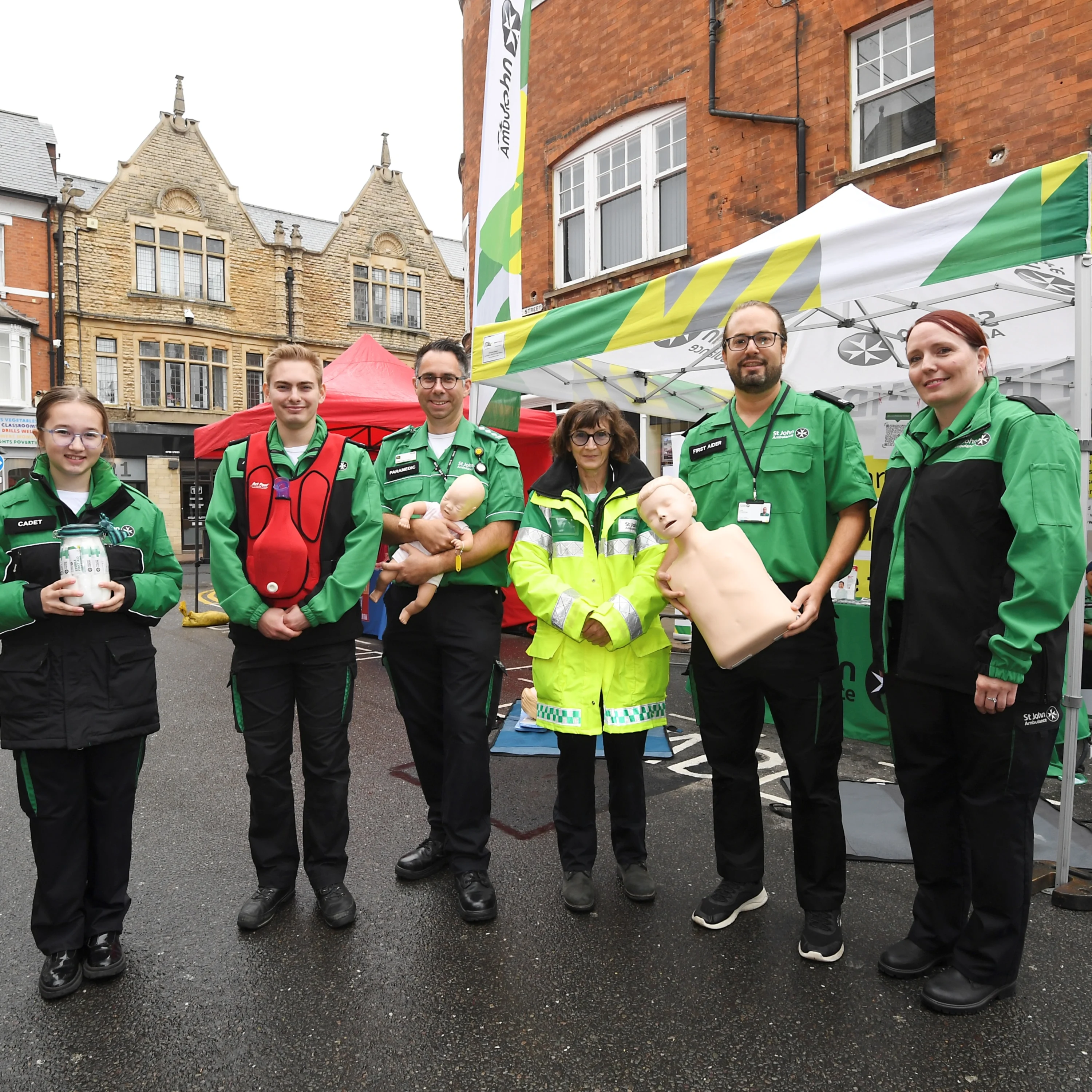 A group of six St john Ambulance first aid trainers in uniform, holding training equipment.
