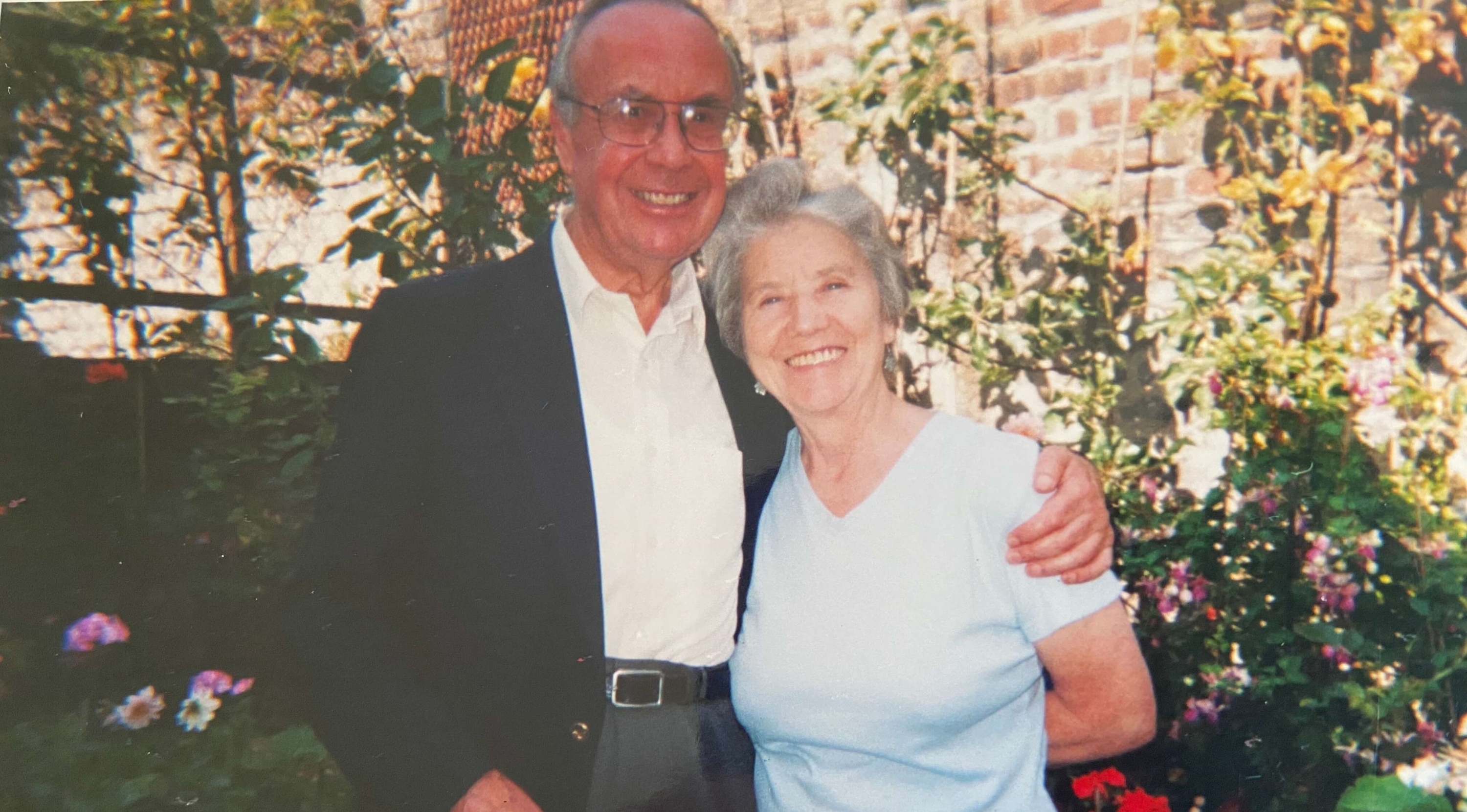 A couple hugging and smiling in front of a floral display.