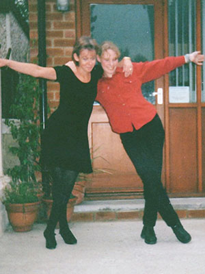 A photograph of Emma and her mum, Yvonne. They have their arms around each other and legs crossed in a courtsey.