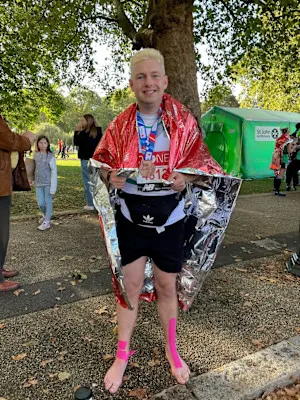 A photograph of David after a run. He's wearing an aluminium blanket and smiling at the camera.