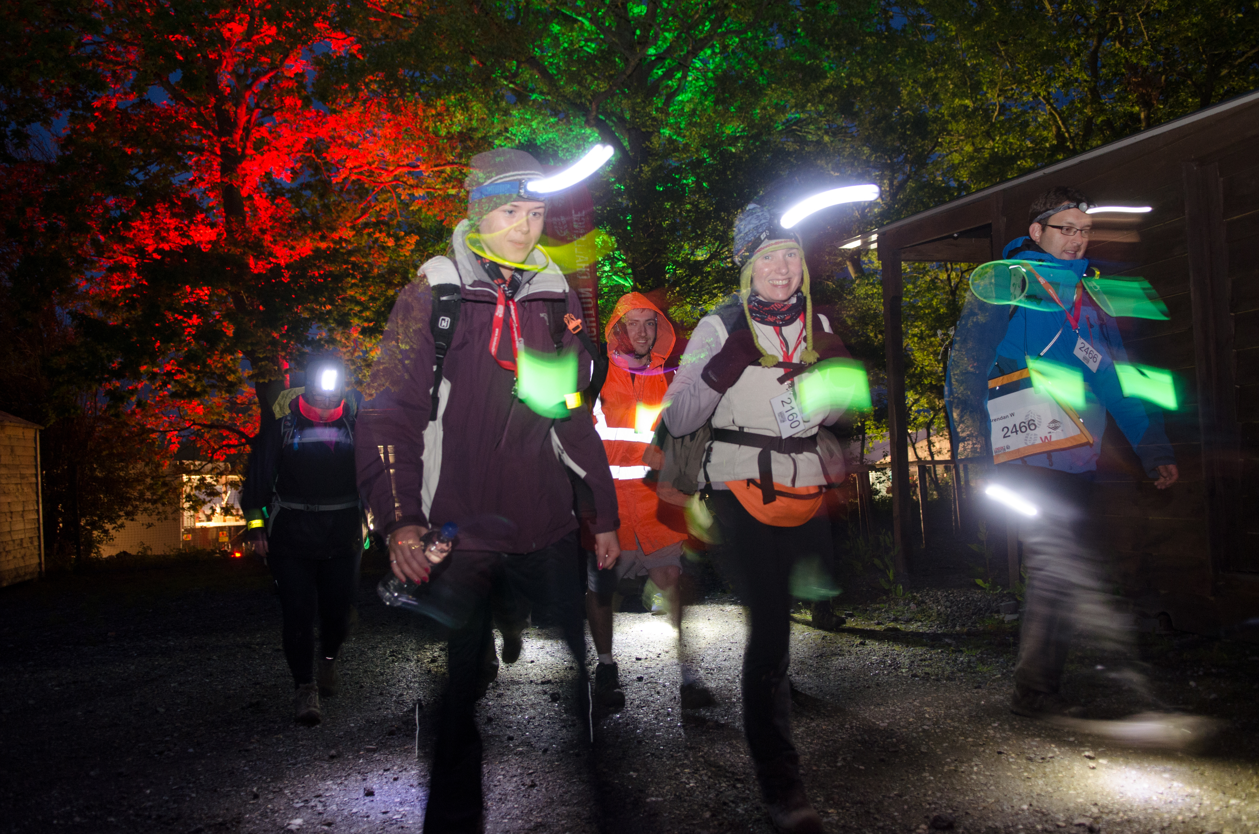 A small group of people taking part in the London Halloween Walk at night with torches and reflective safety items.
