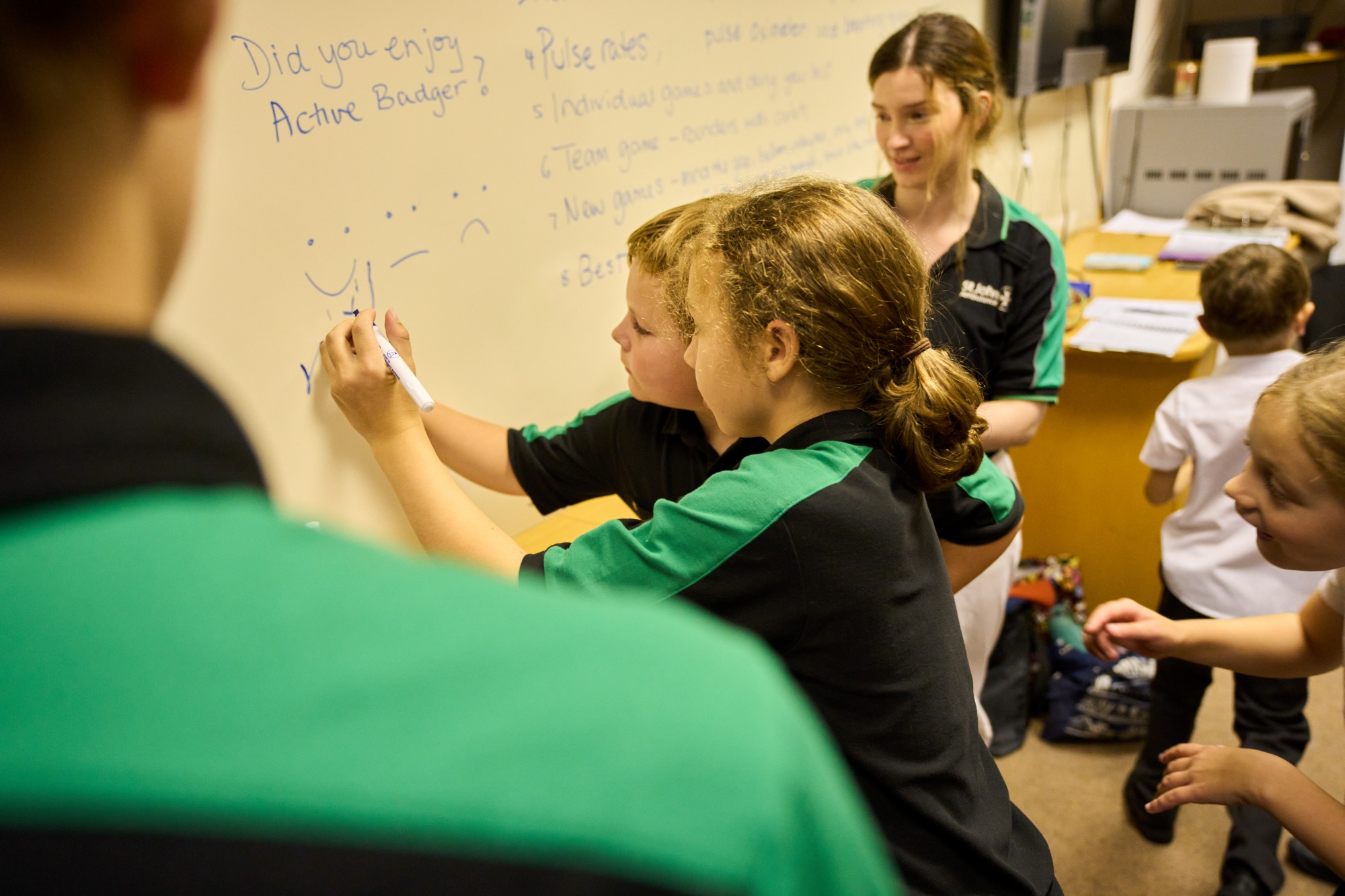 Two St John Ambulance Badgers writing on a whiteboard.