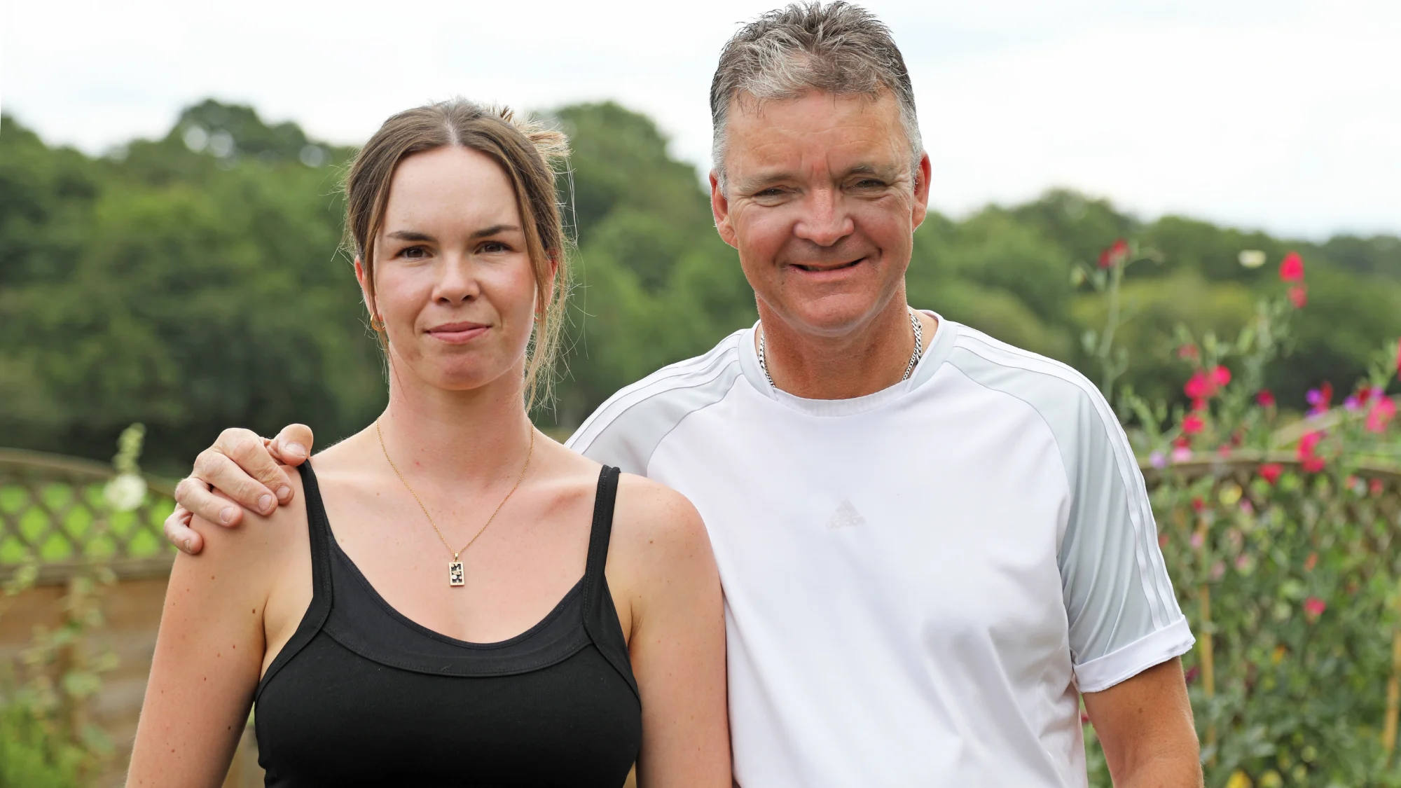 A photograph of Olivia and Gary Pitfield smiling in a garden. Gary has his arm around Olivia.