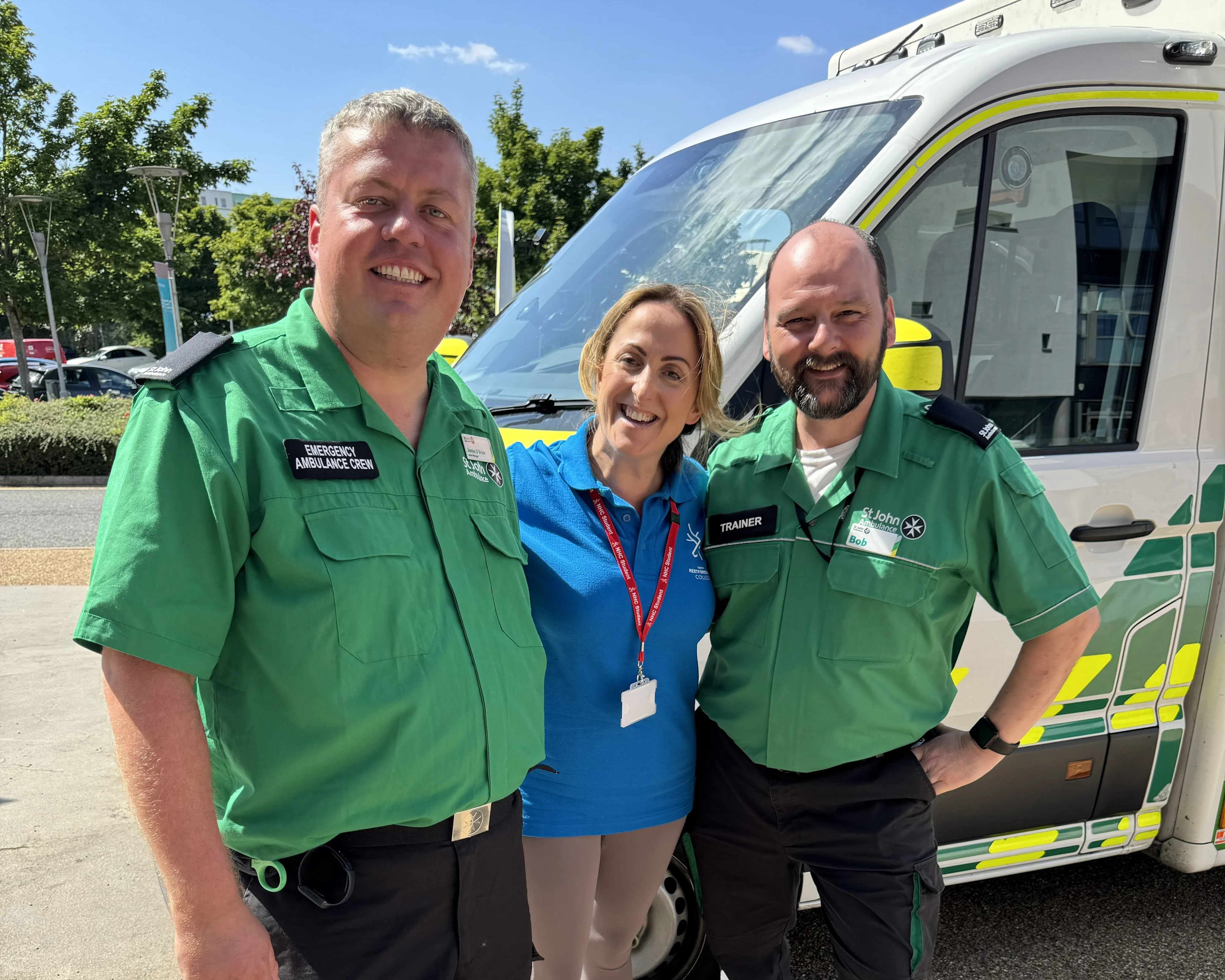 Natalie Cassidy with two St John Ambulance volunteers standing in front of an ambulance.