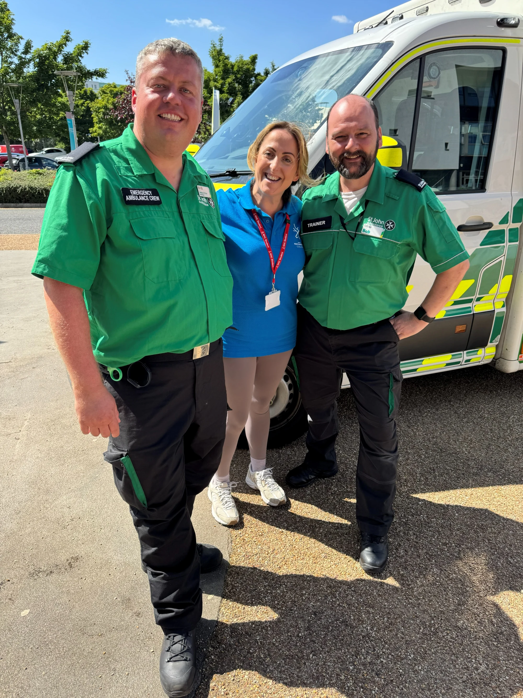 Natalie Cassidy with two St John Ambulance volunteers stood in front of an ambulance.