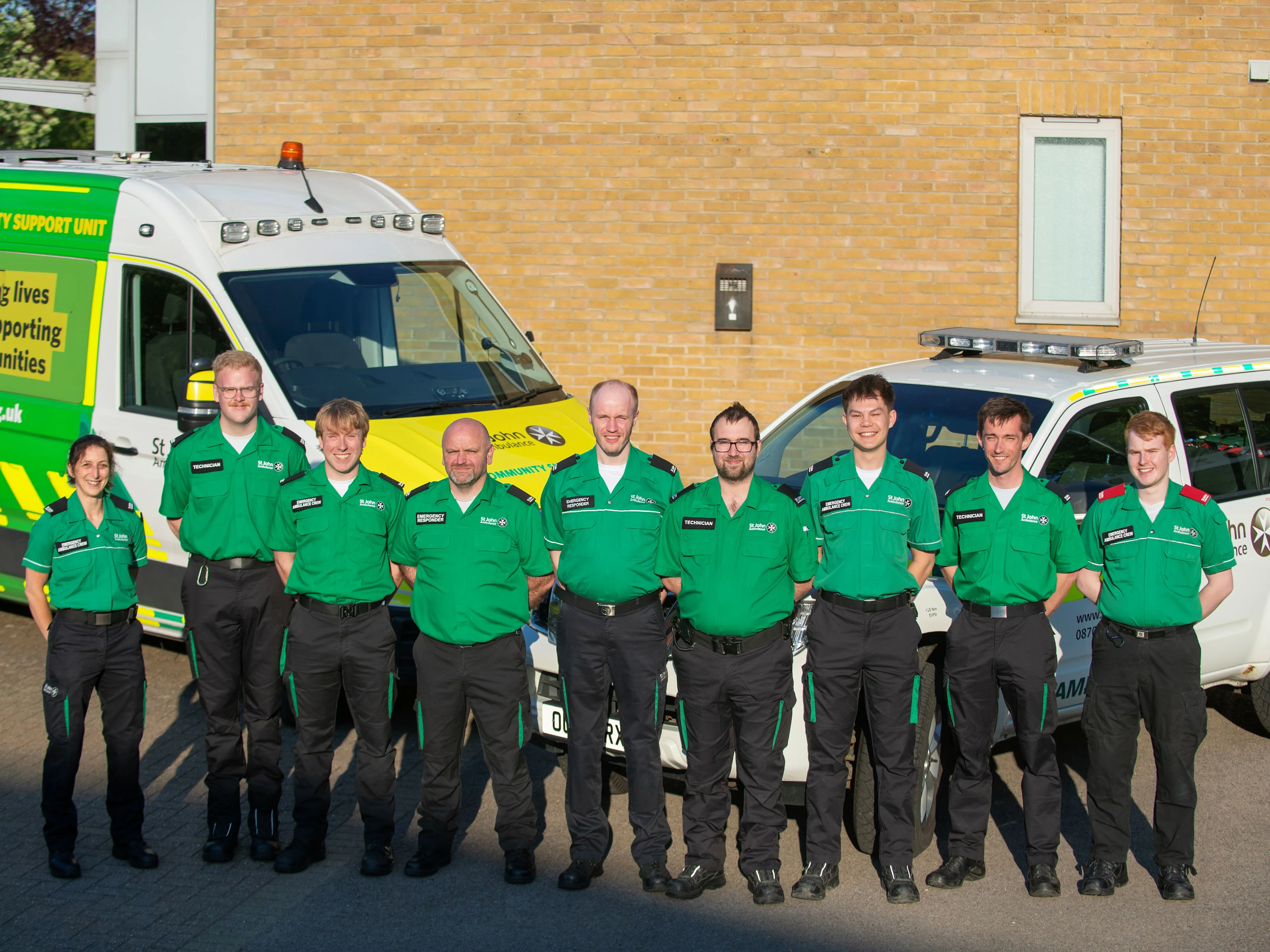 St John Ambulance Co-Responder team stood outside in front of an ambulance and a responder vehicle.