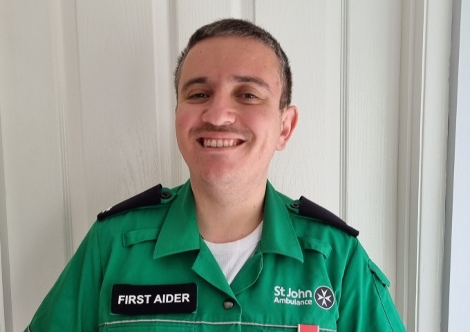 Simon, smiling, and wearing his First Aider uniform.