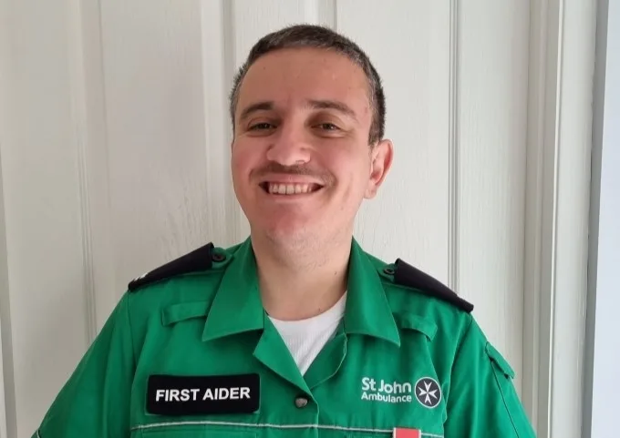 Simon, smiling, and wearing his First Aider uniform.