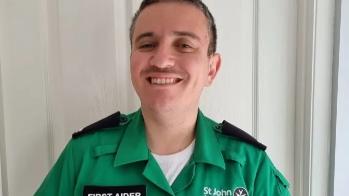 Simon, smiling, and wearing his First Aider uniform.