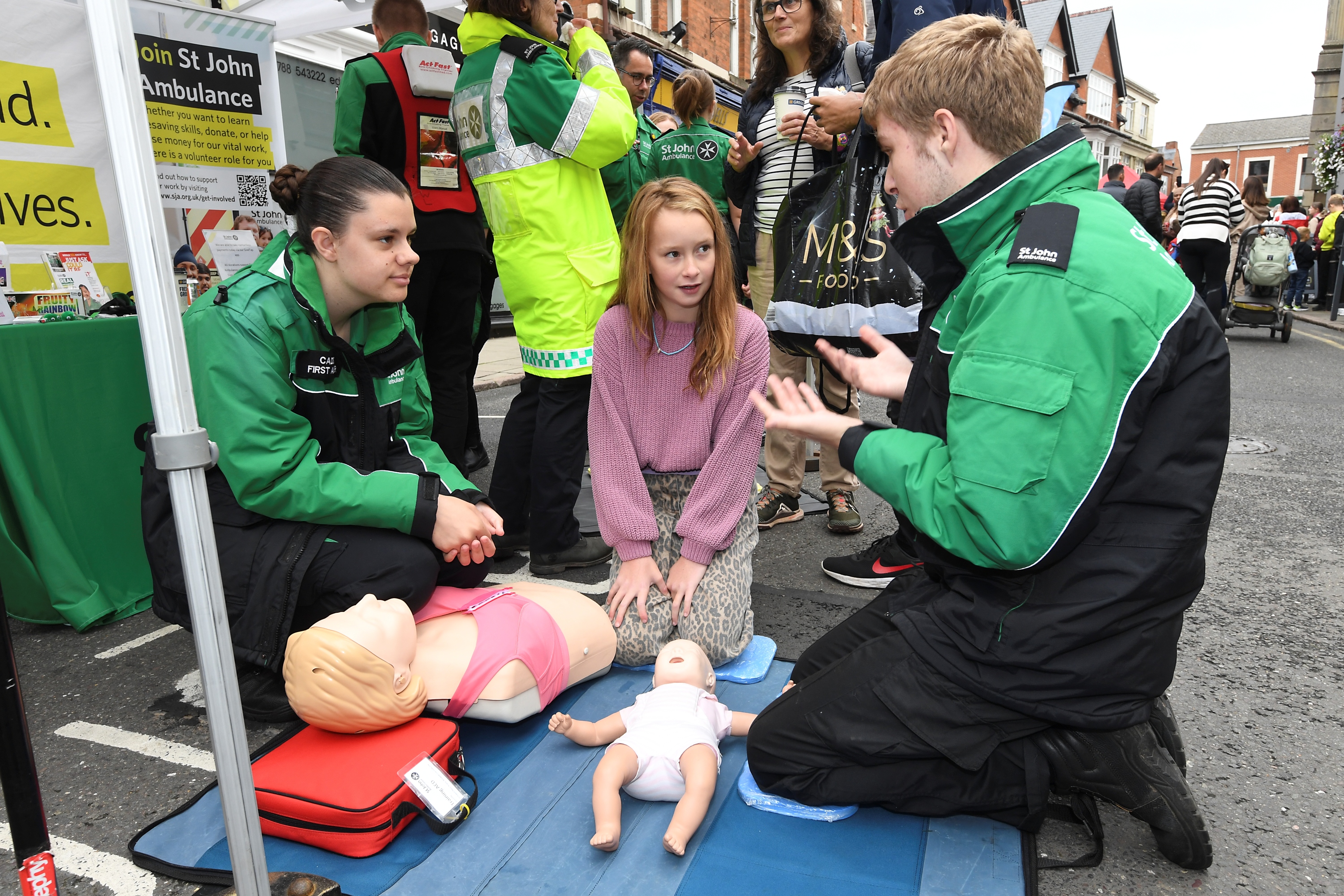 A little girl listening to St John Ambulance volunteers as they give some first aid guidance.