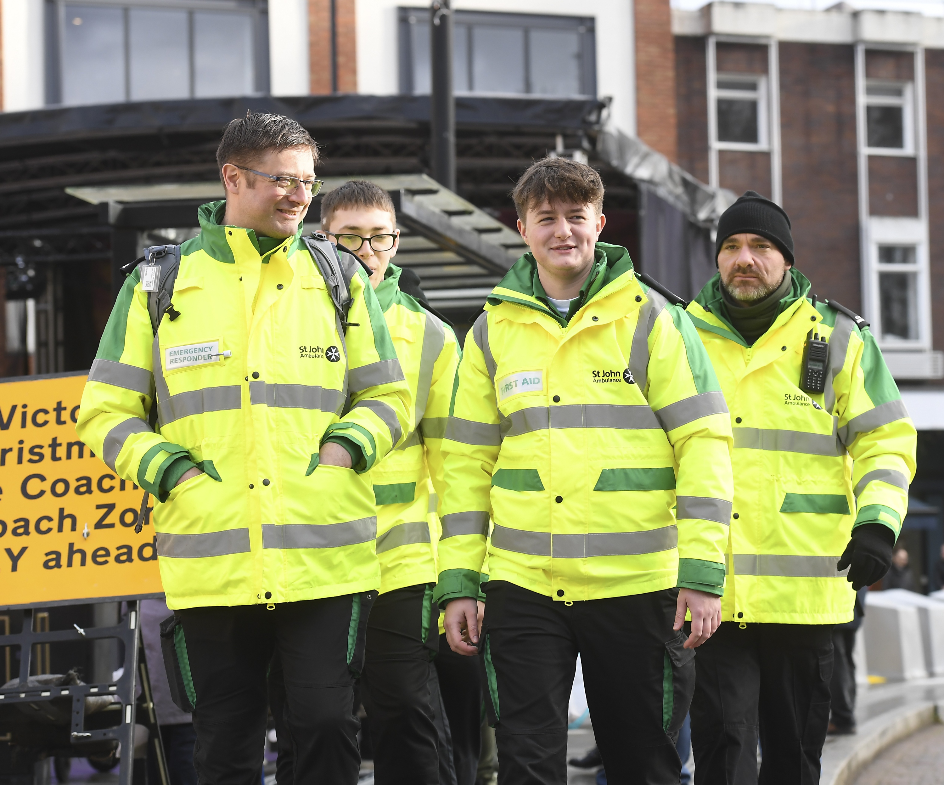 Four Emergency Responder volunteers in high-vis jackets walking along a street. 