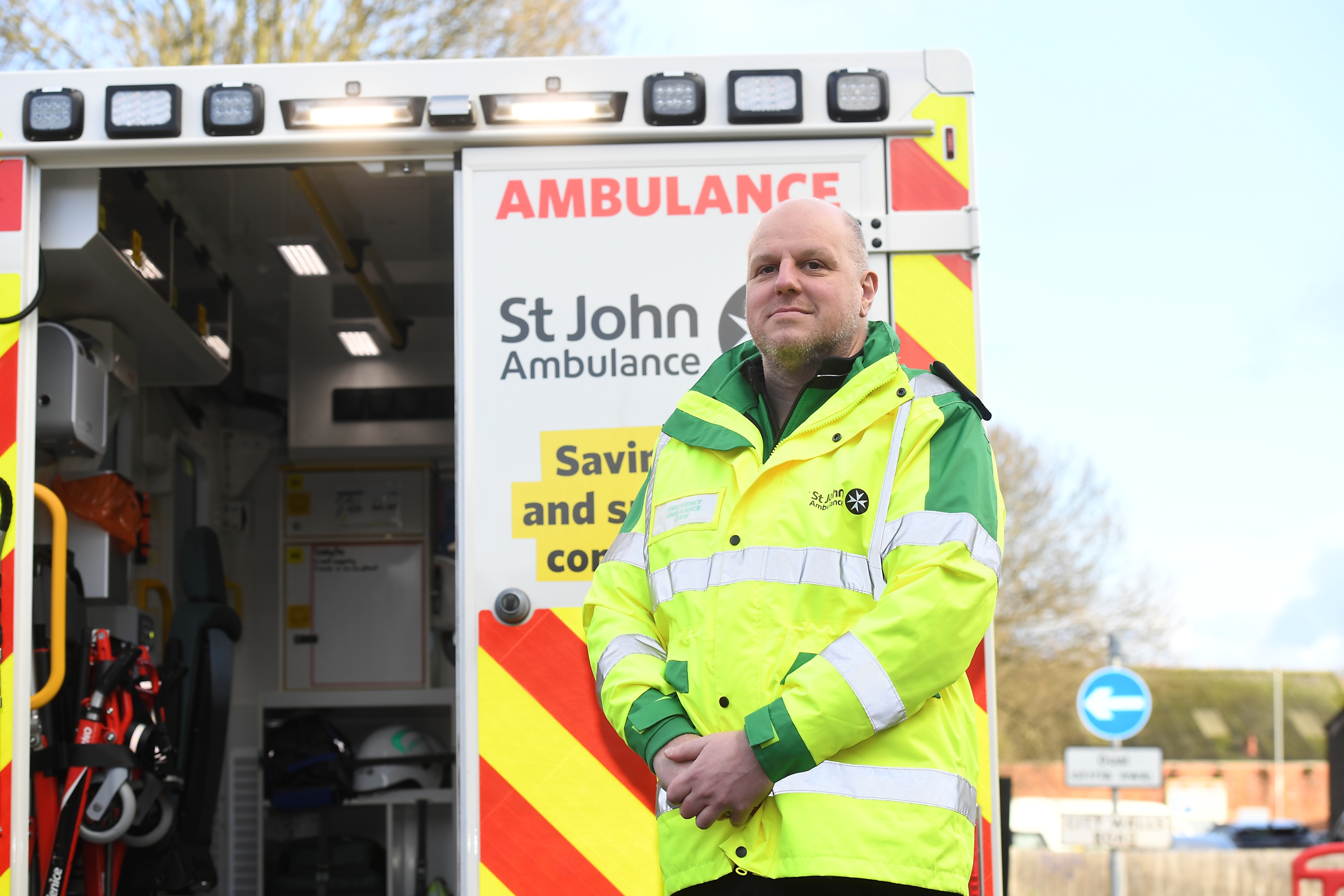 A member of the St John Ambulance emergency crew posing in front of an ambulance with a smile.