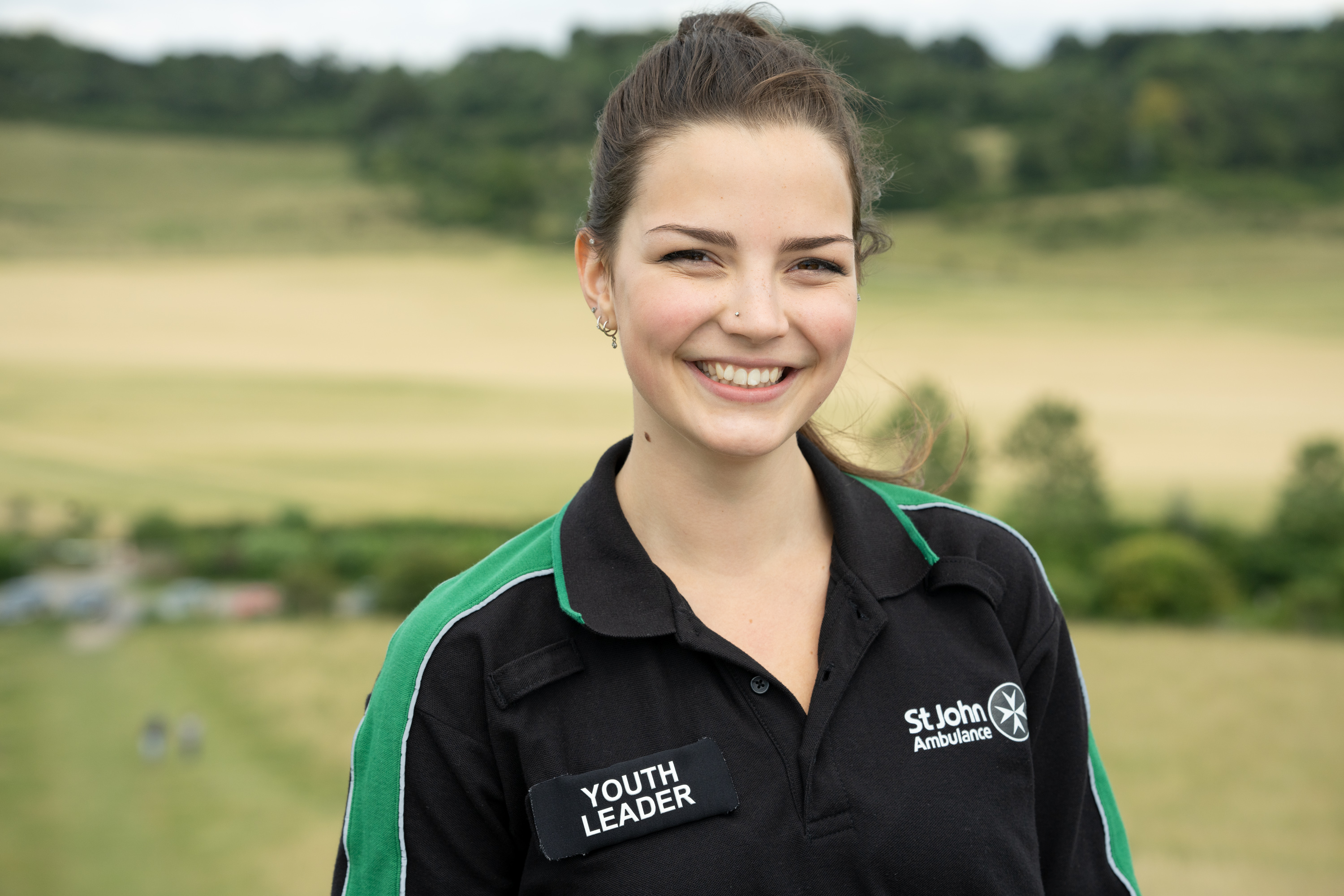 A smiling Youth Leader stood in a field. 
