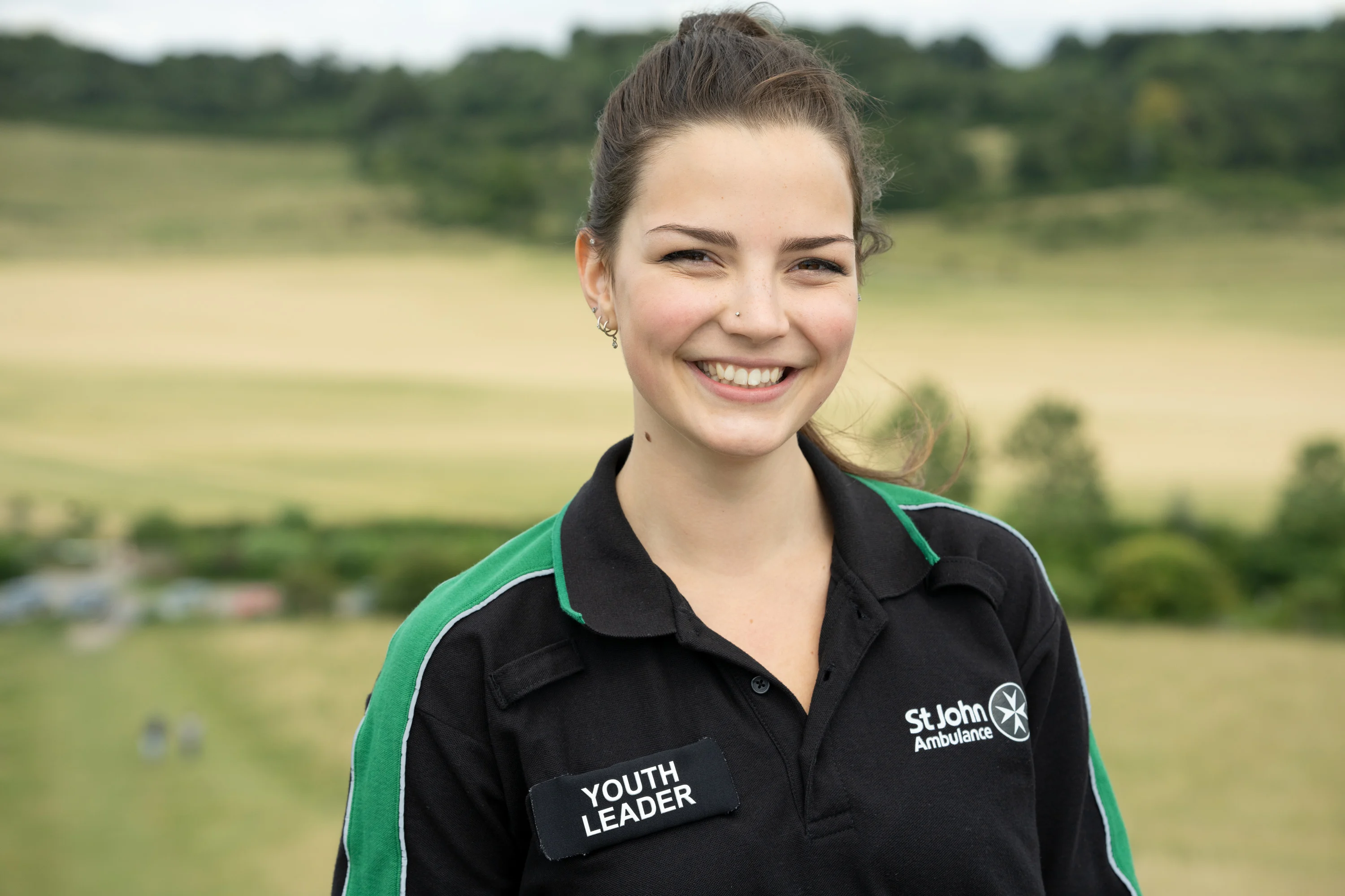 A smiling Youth Leader stood in a field.