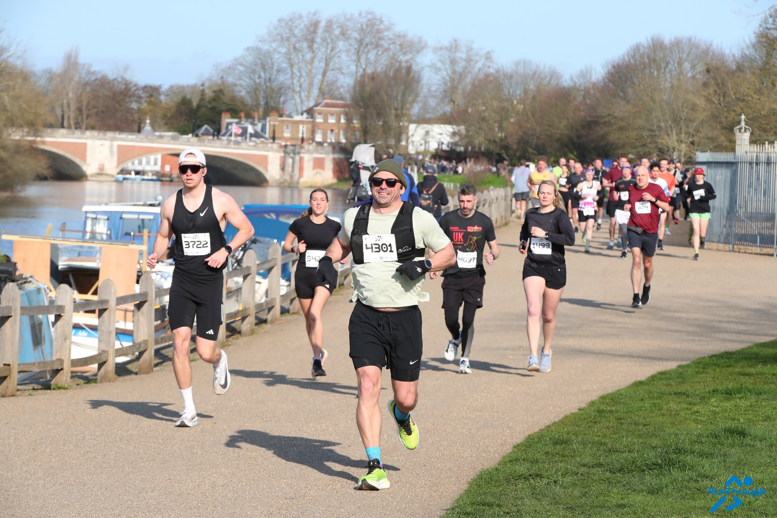 A group of runners at the Hampton Court Palace Half Marathon running along the river. 