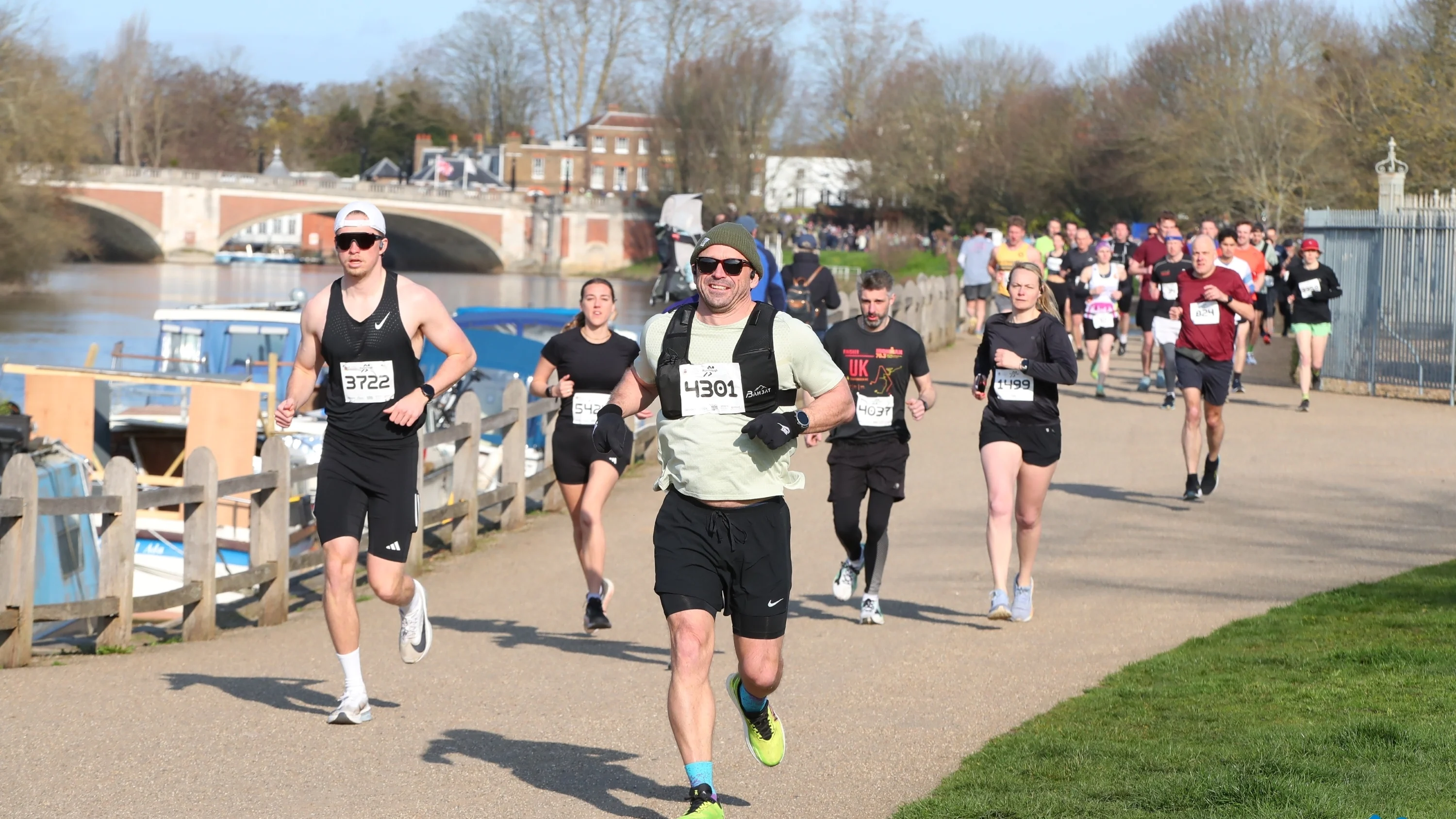 A group of runners at the Hampton Court Palace Half Marathon running along the river.