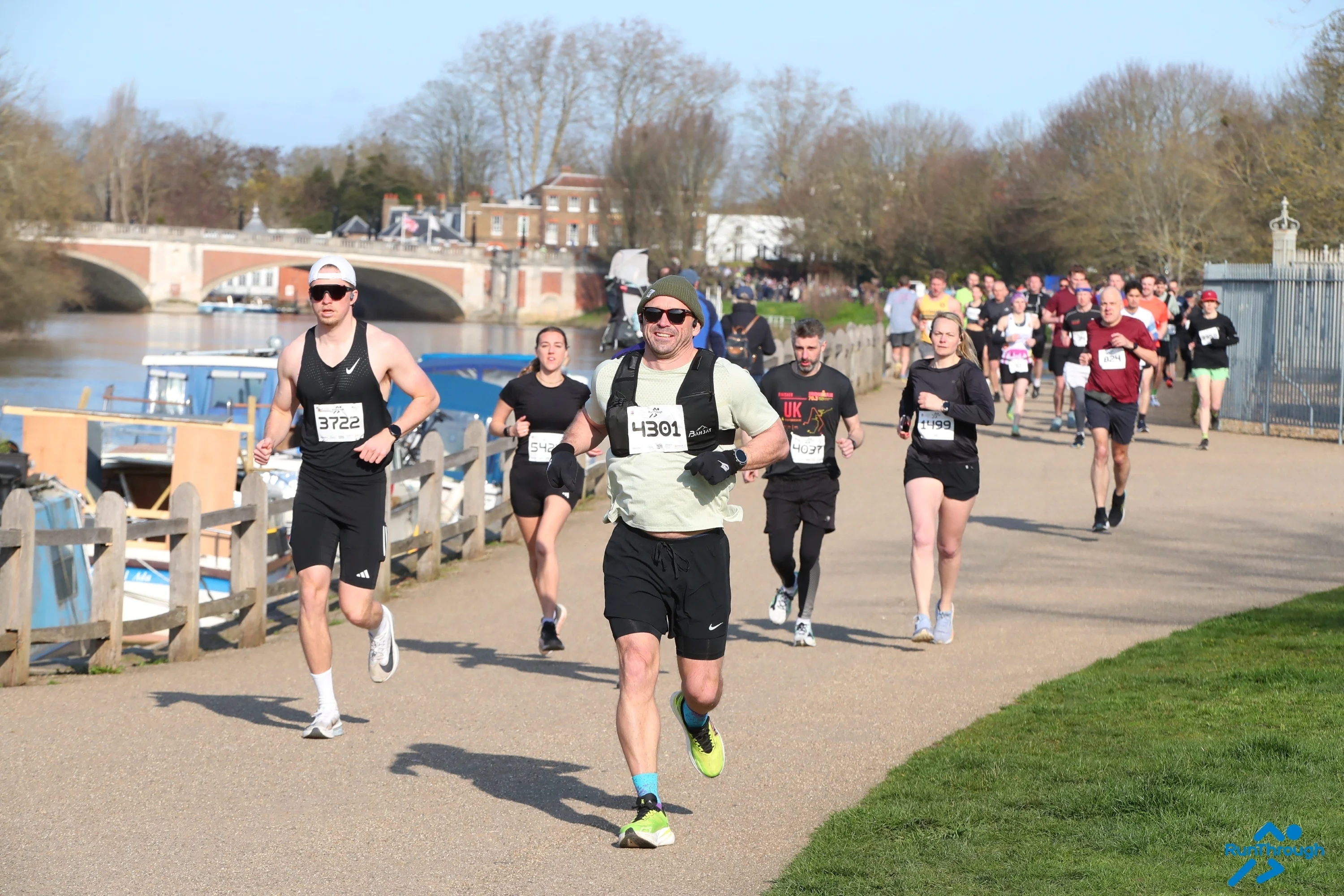 A group of runners at the Hampton Court Palace Half Marathon running along the river.