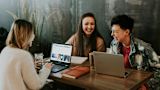 three women around a table workingand laughing together