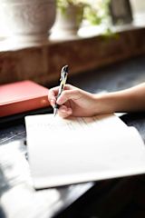 Person writing in a notebook with a pen