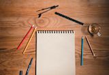 Decorative image of notepad and pencils on wooden desk for article