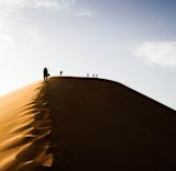 People walking along the ridge of a sand dune