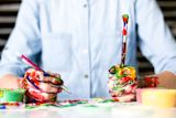 Decorative image of hands holding messy paintbrushes for article