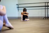 Decorative image of young ballerina with her head in her knees for article