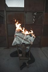 Person reading newspaper on fire