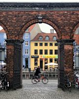 A person riding a bicycle past a brick archway