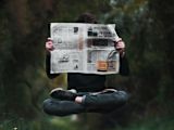 Decorative image of person reading newspaper for article