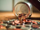 Decorative image of coins falling out of jar for article