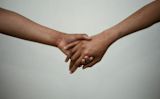 Decorative image of two people holding hands against a plain background for article